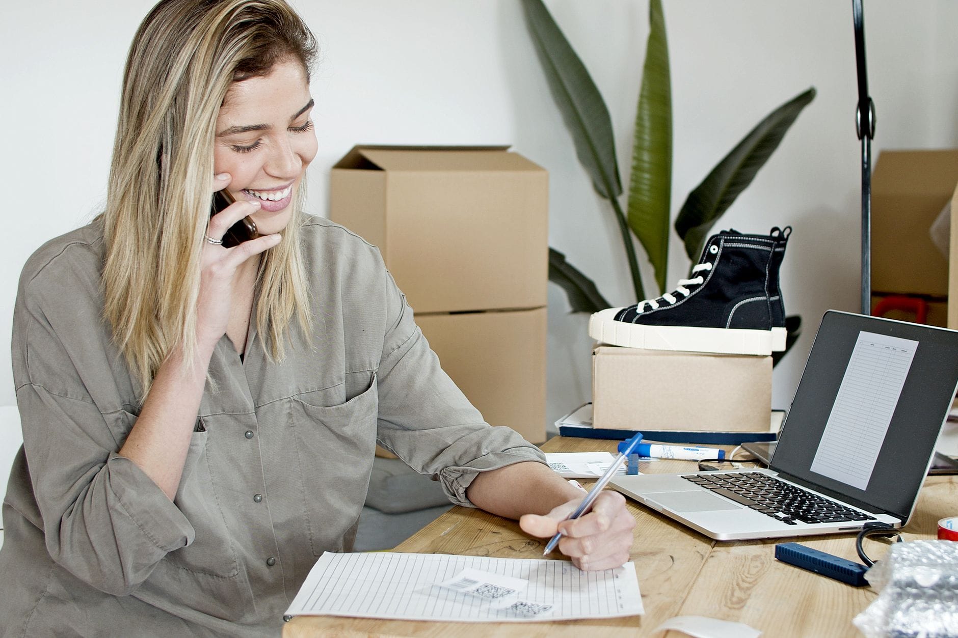 Bizneswoman przy biurku zarządza zamówieniami sklepu online na laptopie i telefo Bizneswoman przy biurku zarządza zamówieniami sklepu online na laptopie i telefo