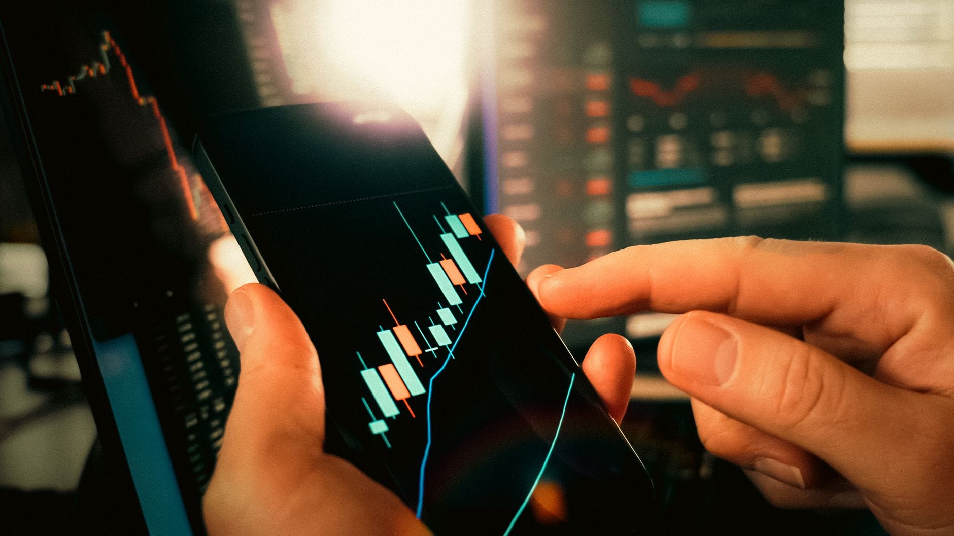 Dłonie przeglądające na smartfonie wykresy finansowe i trendy rynku