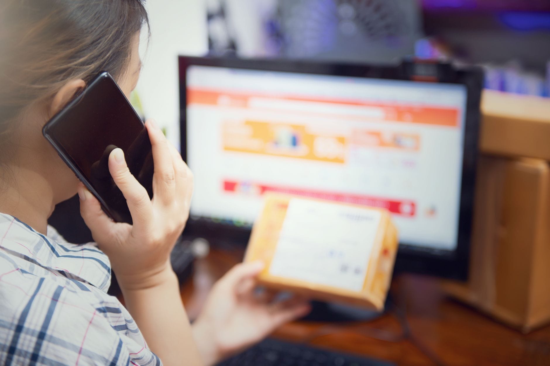 Kobieta w domu korzysta z telefonu i sprawdza paczkę z zakupami online