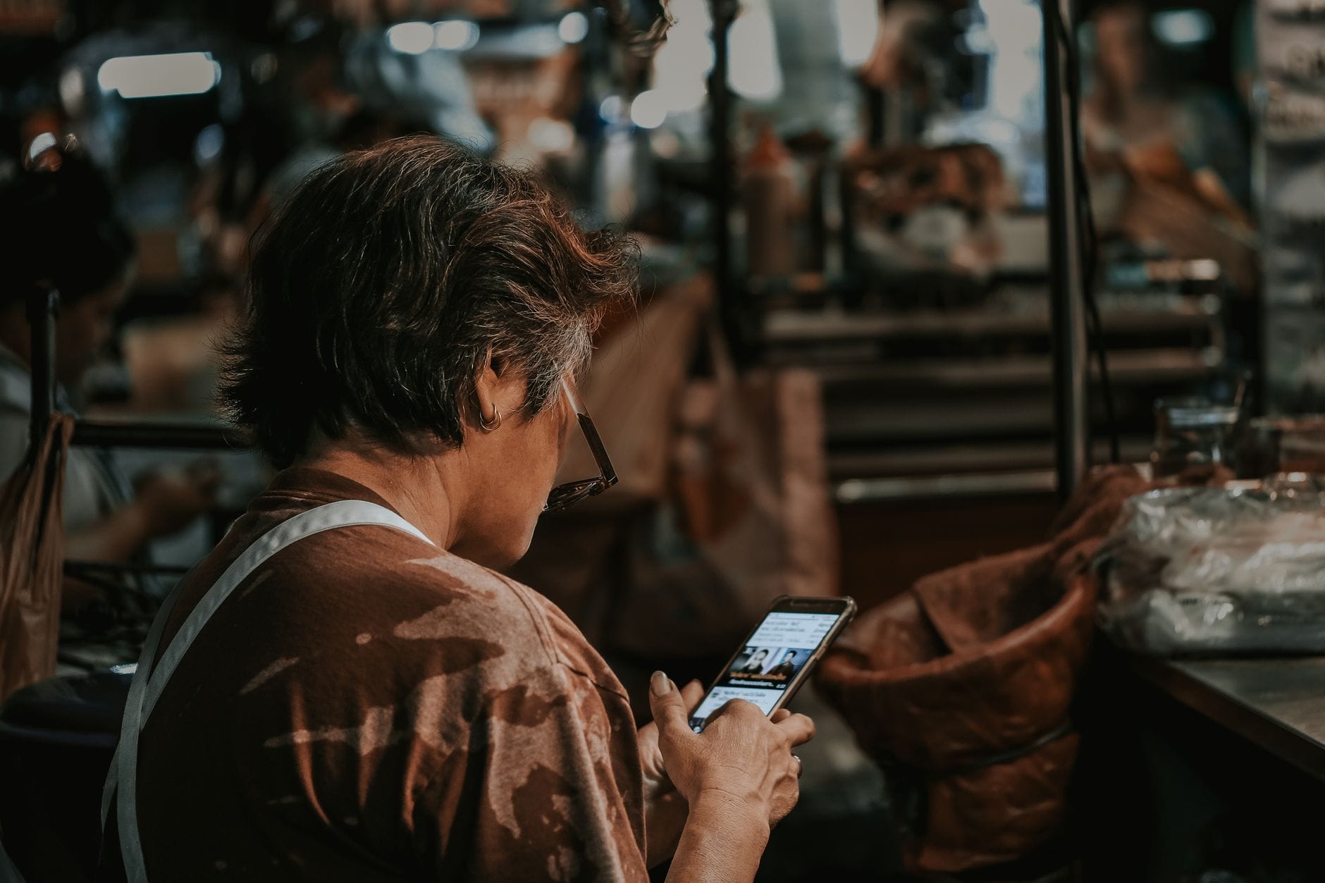 Flipping telefonów na rynku lokalnym małych miast case study zysków, rotacji towaru i konkurencji w ogłoszeniach Kobieta z krótkimi włosami sprawdza smartfon na zatłoczonym targu