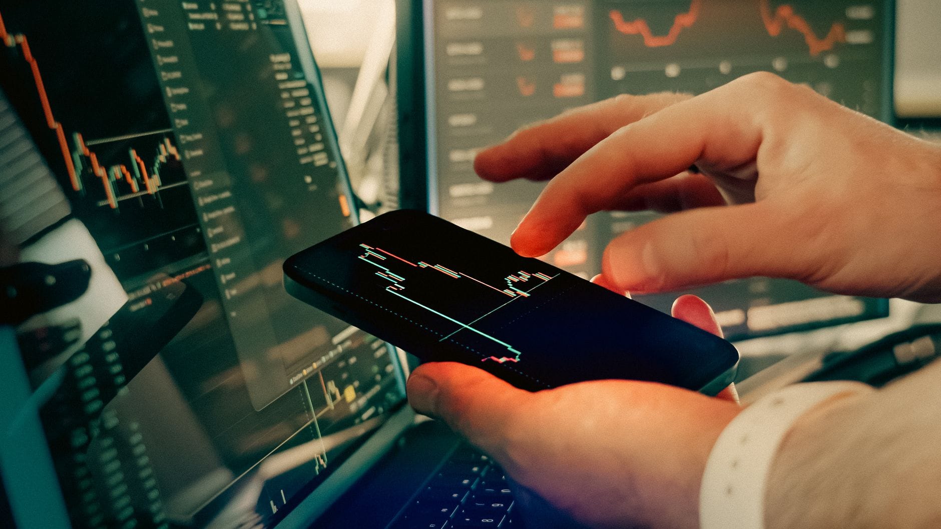 Dłonie analizujące wykresy kryptowalut na ekranie smartfona