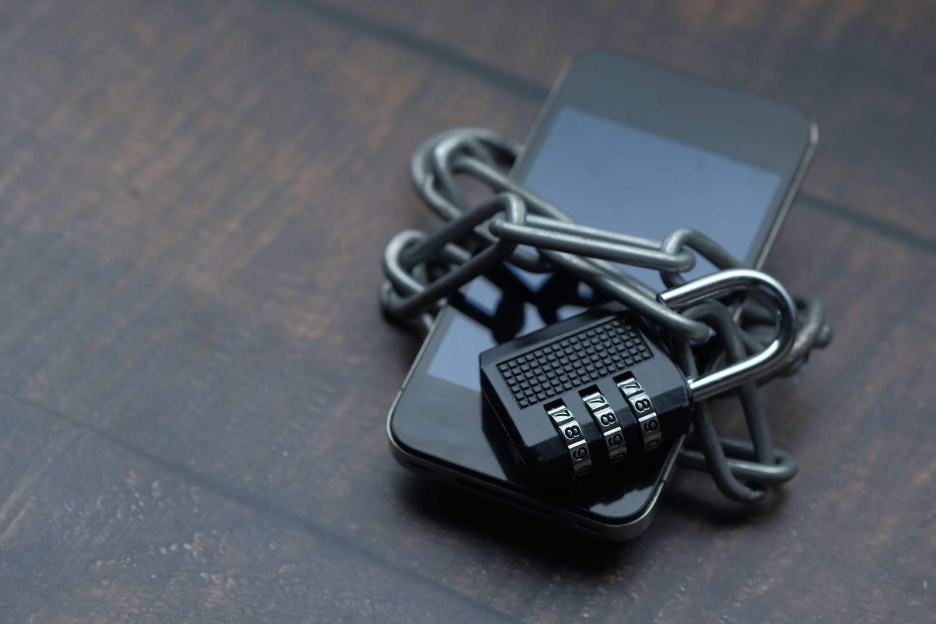 Smartfon opleciony łańcuchem z kłódką symbolizującą bezpieczeństwo Smartfon opleciony łańcuchem z kłódką symbolizującą bezpieczeństwo