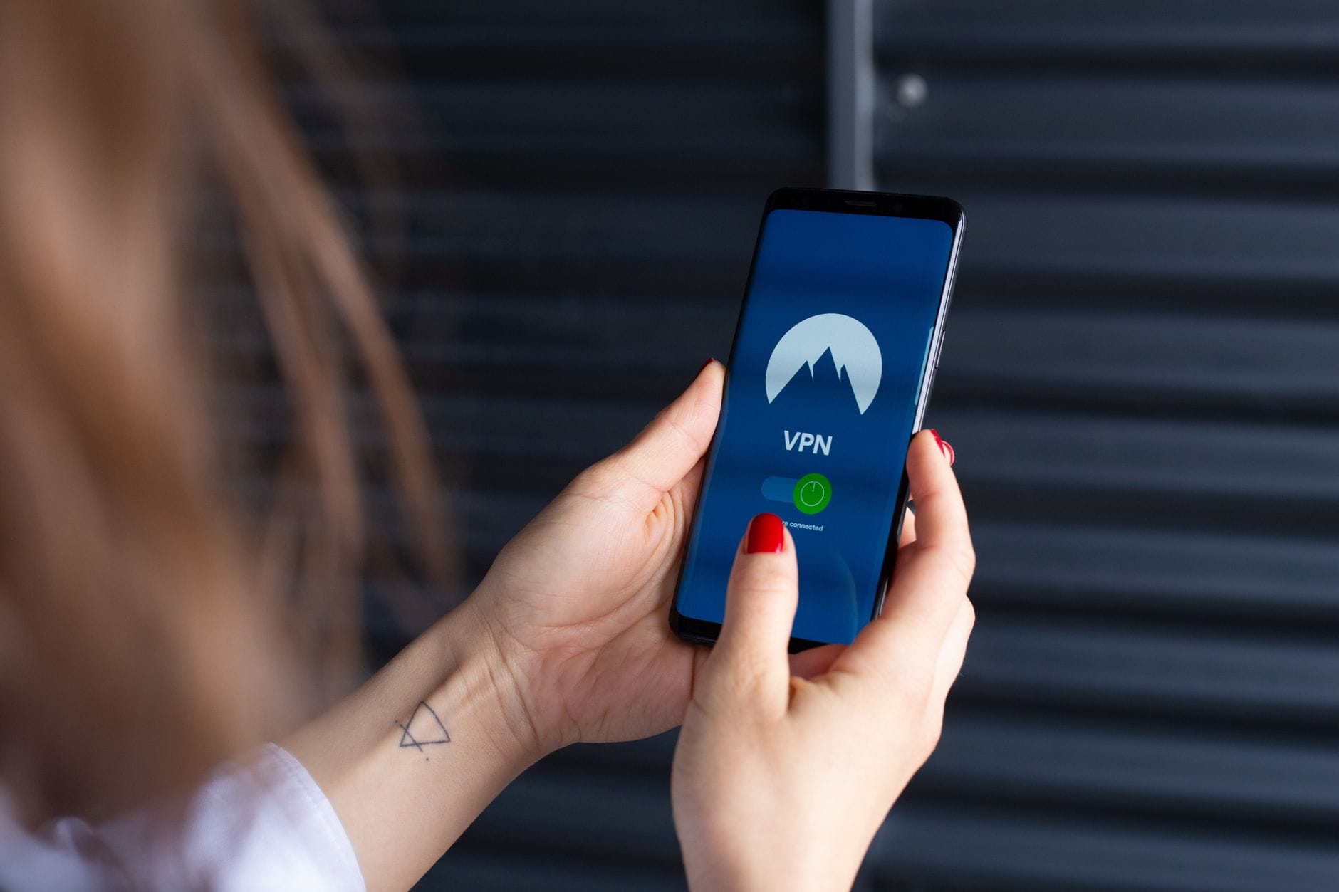 Zbliżenie na dłonie kobiety korzystającej z aplikacji VPN w smartfonie