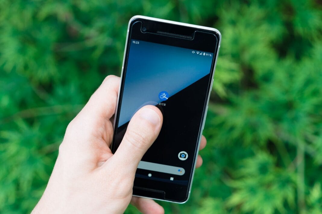 Dłoń trzymająca smartfon z ikoną aplikacji na ekranie outdoors Dłoń trzymająca smartfon z ikoną aplikacji na ekranie outdoors